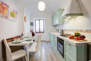 多利亚尼Dogliani Borgo Castello - Happy Rentals的厨房配有绿色橱柜和一张带一碗水果的桌子
