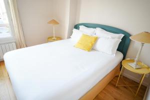 布洛涅-比扬古Villa Escudier Appart-hôtel的卧室配有一张白色大床和黄色枕头