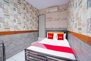 BungurasihOYO 91415 De Wijaya Hotel的一间卧室配有一张带红色枕头的床