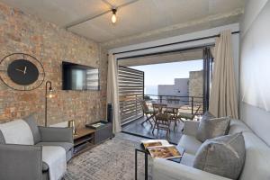 布鲁堡史特兰Manhattan on Coral 7的客厅配有沙发和砖墙电视