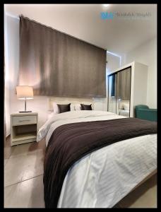 安曼Weibdeh Heights Apartments的一间卧室设有一张大床和大窗户