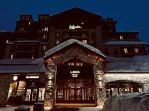 蒂涅Hôtel Tignes Le Diva的屋顶上积雪的建筑物前的商店