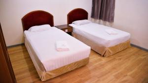 拉布安Sogo Hotel 2的小型客房铺有木地板,配有两张床。
