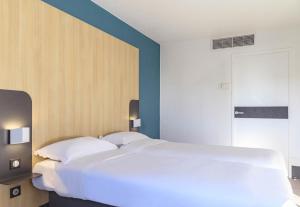 尼姆B&B HOTEL Nîmes Centre Arènes的蓝色墙壁的房间里一张大白色的床