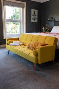 马舍姆耕地旅馆的卧室里一张黄色的沙发,卧室里配有一张床