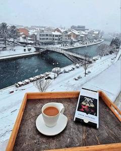 斯特鲁加Struga Riverview Hotel的坐在桌子上边看书边喝杯咖啡