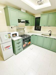 利雅德شقة بغرفتين نوم وبلكونة خاصة ١٥的厨房配有绿色橱柜、炉灶和冰箱。