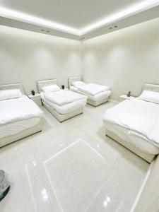 利雅德شقة بغرفتين نوم وبلكونة خاصة ١٥的白色客房的三张床,铺有白色地板