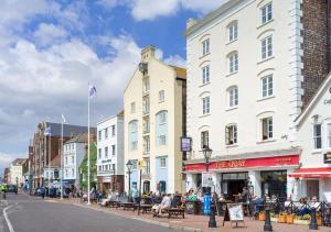 浦耳Sea view apartment on Poole Quay overlooking Sandbanks的一条城市街道,人们坐在楼前的长椅上