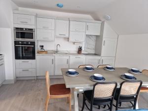 亨斯坦顿Beach Penthouse, Hunstanton Norfolk的厨房配有白色橱柜和桌椅