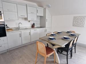 亨斯坦顿Beach Penthouse, Hunstanton Norfolk的厨房配有白色橱柜和一张带椅子的木桌