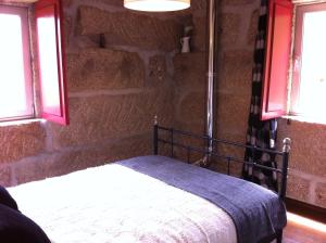 佩纳菲耶尔Eira das Carvalhas的卧室配有一张石墙床