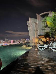 吉隆坡Empire Hostel Regalia的夜间躺在泳池旁的木板路上的人