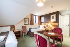 克劳利Barrington Lodge的酒店客房带两张床和一张桌子以及椅子。