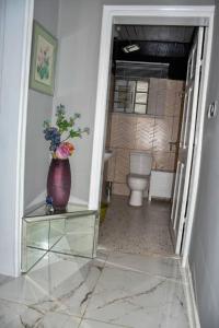 林贝Movomo Limbe的浴室设有卫生间和玻璃桌上的花瓶