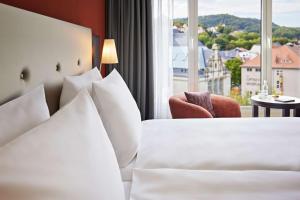 耶拿Dorint Hotel Esplanade Jena的酒店客房设有白色的床和窗户。