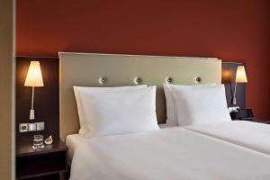 耶拿Dorint Hotel Esplanade Jena的卧室配有带白色枕头的大床