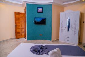 AheroCalfie Resort Kisumu的一间卧室配有一张床,墙上配有电视