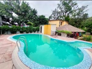 兰纳加Mannat Corbett Resort的一座房子前面的蓝色海水游泳池