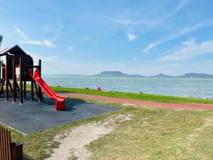 福纽德Balaton lake view 30 m from Beach的水边的游乐场,有红色滑梯