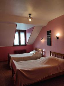 Pont-de-Poittehotel de l'ain的配有粉红色墙壁的客房内的两张床