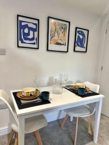 特罗布里奇Spacious and Stylish Flat in Trowbridge, Wiltshire的一张带两把椅子的白色桌子和一张带盘子的桌子