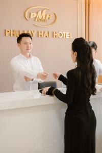 岘港Phu My Hai Hotel的站在旅馆柜台的男女
