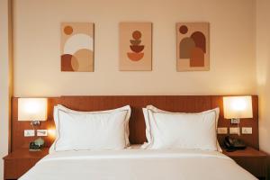亚的斯亚贝巴AYA Addis Hotel的一间卧室配有一张带两个枕头和两个灯的床。