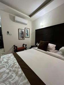 Al Bunayyāt al JanūbīyahLB Hotel的卧室配有一张白色大床和一把椅子