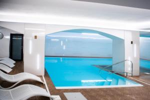 奥什恰德尼察马琳酒店的游泳池位于带白色椅子的房间中间
