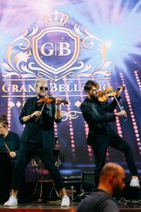 巴统Grand Bellagio Batumi Convention & Casino Hotel的两个男人在乐队的舞台上演奏小提琴