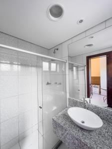 伊塔帕里卡Itaparica praia hotel的一间带水槽和玻璃淋浴的浴室