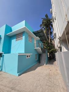 钦奈SAIBALA HOMESTAY - AC 1 BHK NEAR AlRPORT的一座蓝色的建筑,有楼梯和棕榈树