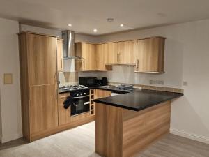巴塞尔顿Impeccable 2-Bed House in Basildon的厨房配有木制橱柜和黑色台面
