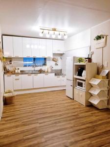 首尔Jamsil Heaven的厨房铺有木地板,配有白色橱柜。