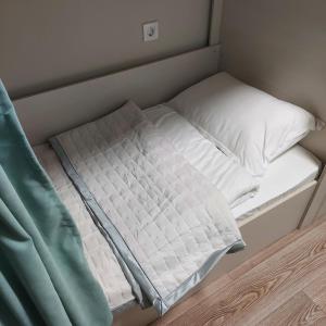 阿拉木图Hostel Nomad的一张小床,配有白色床单和枕头