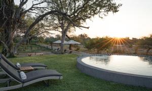 LentswelemoritiKolokolo Safari Home的公园旁的游泳池设有2个长椅,享有日落美景