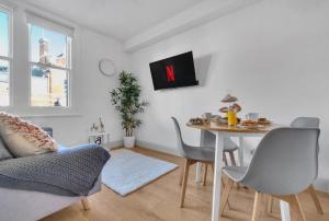 伦敦homely - West London Apartments Putney的客厅配有桌子和墙上的电视