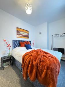 巴恩斯利Cosy home in Barnsley centre的一间卧室配有一张带橙色毯子的床