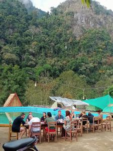 Ban NongkhamNongKhiaw CampingSite Swimming Pool的一群人坐在游泳池附近的桌子旁