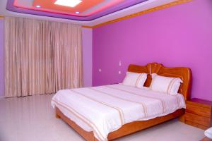 布琼布拉lake palace beach hotel的一间卧室设有一张紫色墙壁的大床