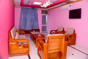 布琼布拉lake palace beach hotel的一间设有粉红色墙壁和桌椅的房间