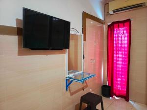 肯达利OYO 93278 Wisma Syariah Lahundape的墙上的平面电视,带有红色窗帘