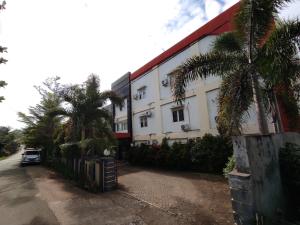 肯达利OYO 93278 Wisma Syariah Lahundape的一座白色的建筑,前面有棕榈树