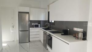尼科西亚Hypnos Residence的厨房配有白色橱柜和不锈钢冰箱