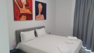 尼科西亚Hypnos Residence的卧室配有一张白色床,墙上挂有三幅画作