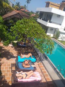 尼甘布内贡博绿树住宿加早餐旅馆的两人在游泳池旁的毛巾上躺着