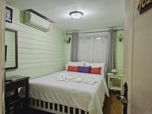 曼谷W home The Thai-style tranquil and cozy villa的一张床位,房间配有绿色和红色枕头