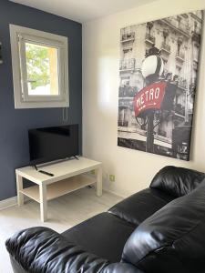 OsnyStudio cosy indépendant avec Jardin à Osny proche Cergy pontoise的客厅配有黑色真皮沙发和电视