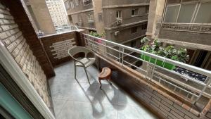 开罗New Cozy Apartment 5 Minutes away from Cairo Airport and all Amenties的坐在大楼阳台的椅子